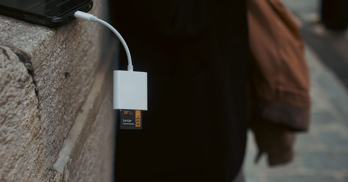 a white usb-c card reader plugged into a phone holding a memory card